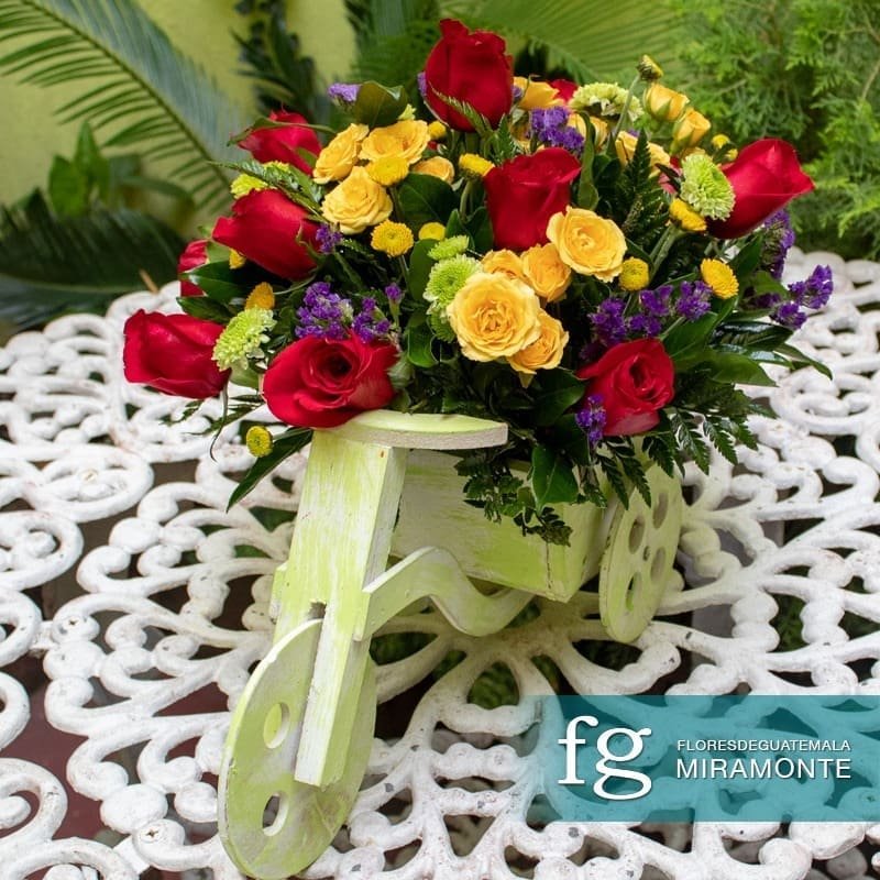 Red and yellow roses displayed on a decorative pale-green wooden cart.